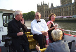 伦敦千禧号游船经过国会大厦，客人在游船上举行私人聚会，客人在顶层甲板上畅聊